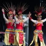 三个女人戴着五颜六色的印尼羽毛头饰跳舞, 黄色的裙子, 还有串珠腰带和衣领.